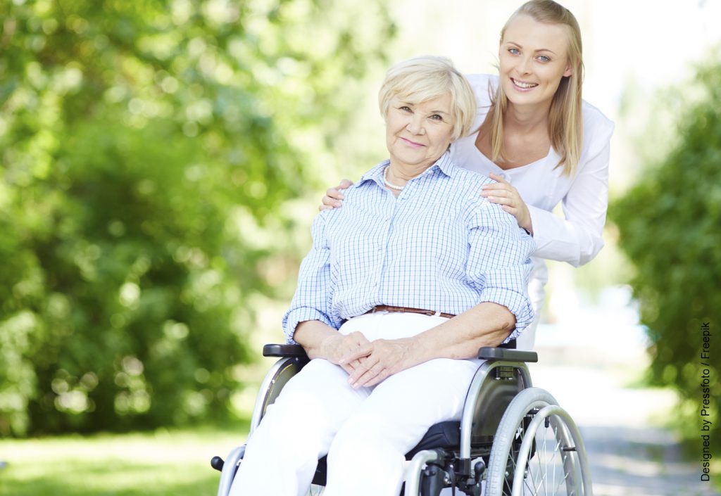 Rollstuhlfahrerin im Park mit Krankenpflegerin
