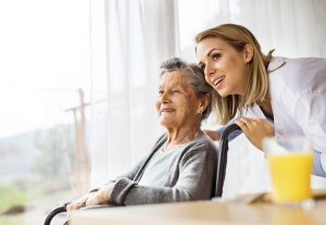 ältere Dame schaut mit einer Krankenschwester aus dem Fenster